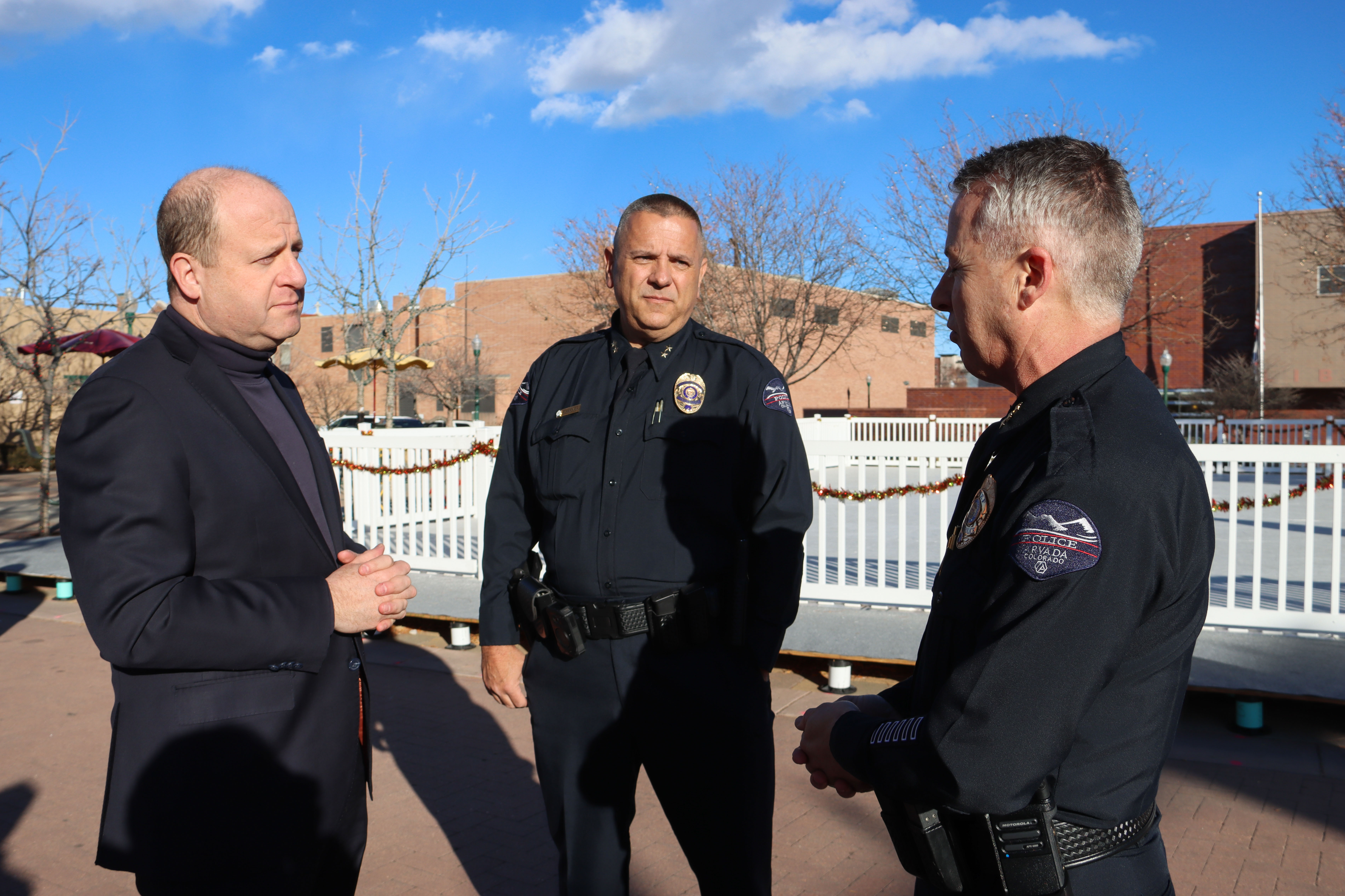 Governor Polis speaking to Arvada Police Chief Ed Brady and Deputy Police Chief Todd Reeves. 