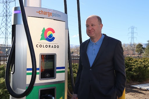 Governor Polis stands next to ChargePoint Charger