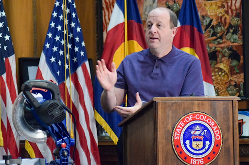 Governor Polis speaks in his office before cutting through 208 old executive orders with a chop saw. 